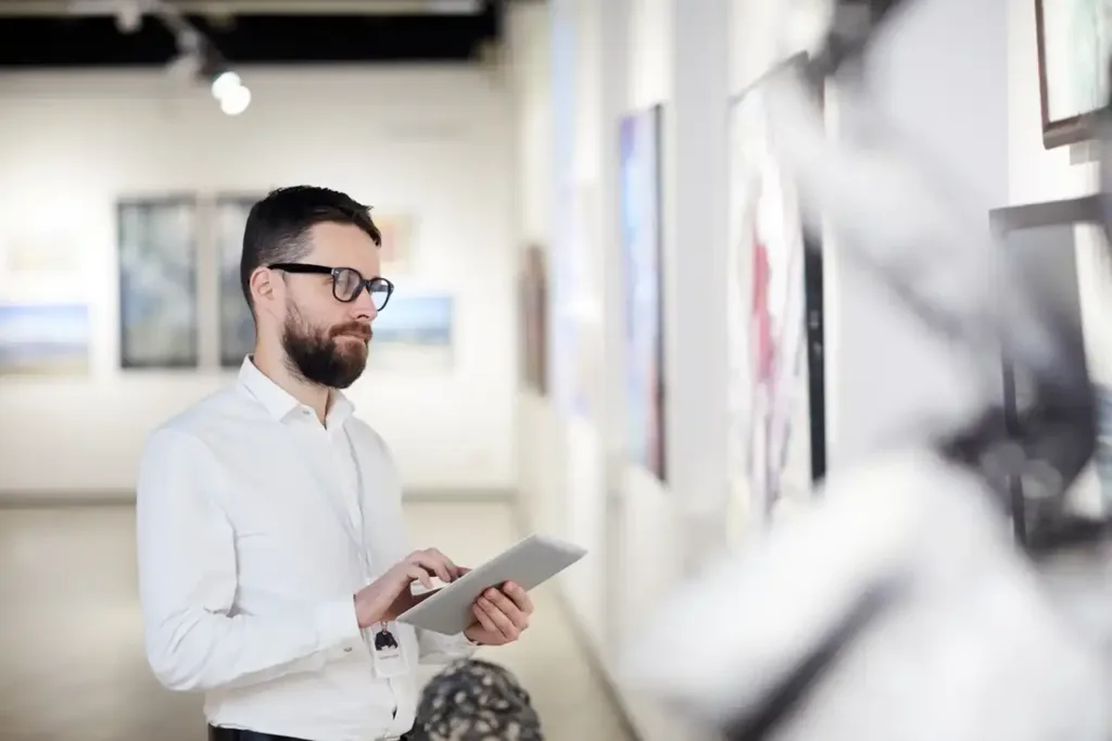 Waist up portrait of bearded art gallery manager using digital tablet while organizing exhibition in museum, copy space