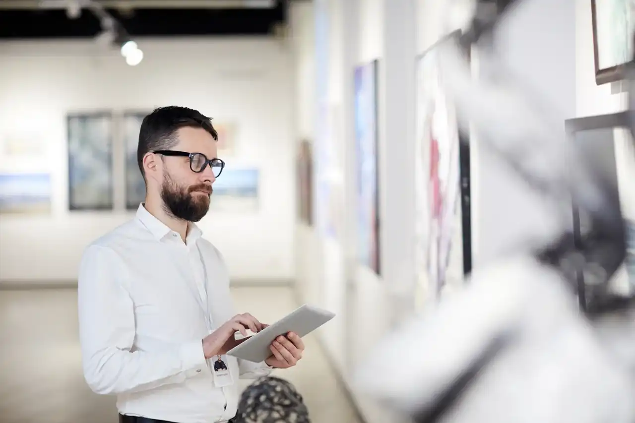 Waist up portrait of bearded art gallery manager using digital tablet while organizing exhibition in museum, copy space