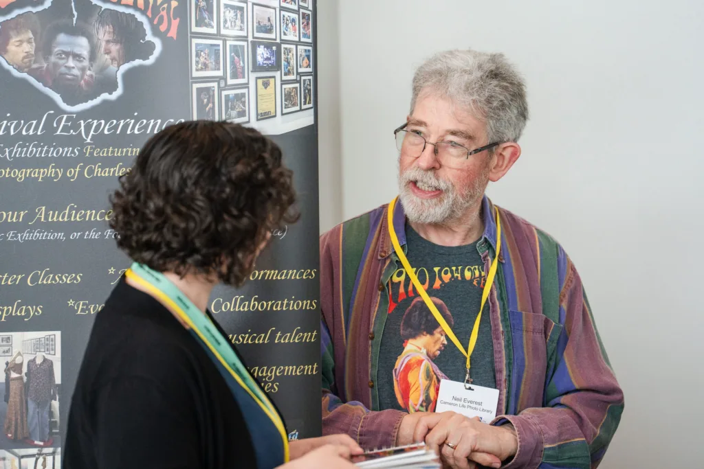 Older man by pull up stand talking to curly haired woman